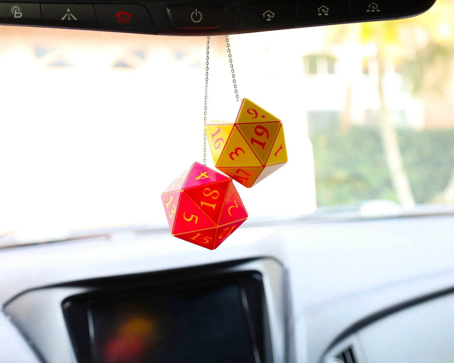 Red and yellow twenty-sided dice hanging from a car mirror as a charm accessory