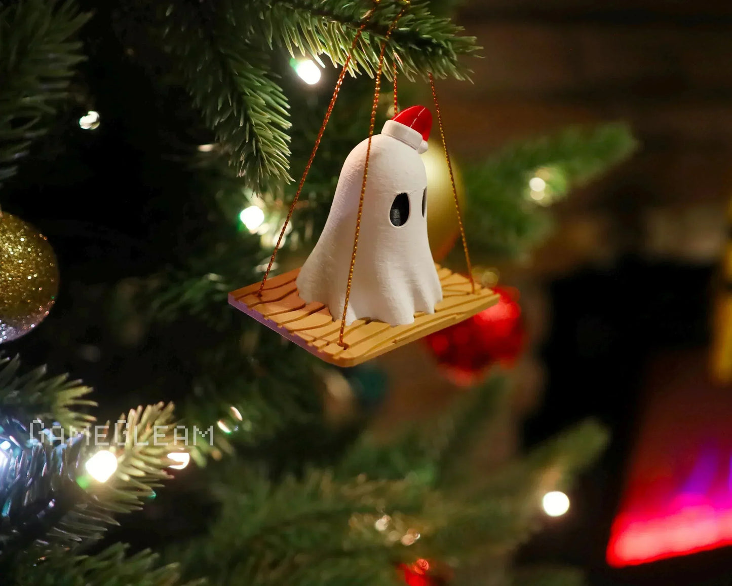 Handmade ghost ornament with Santa hat on wooden swing, hanging on Christmas tree