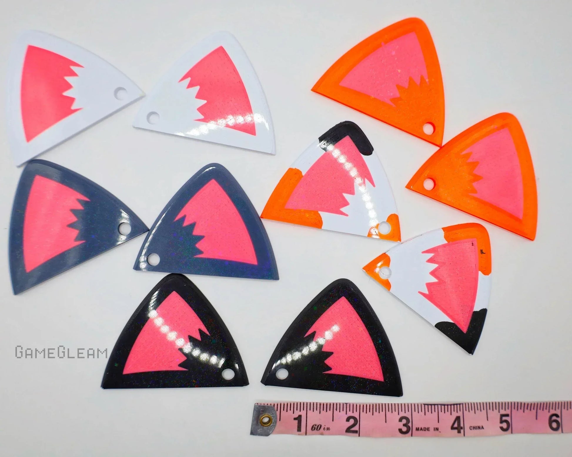 Colorful acrylic cat ear charms in white, black, and orange with pink centers, measured for scale