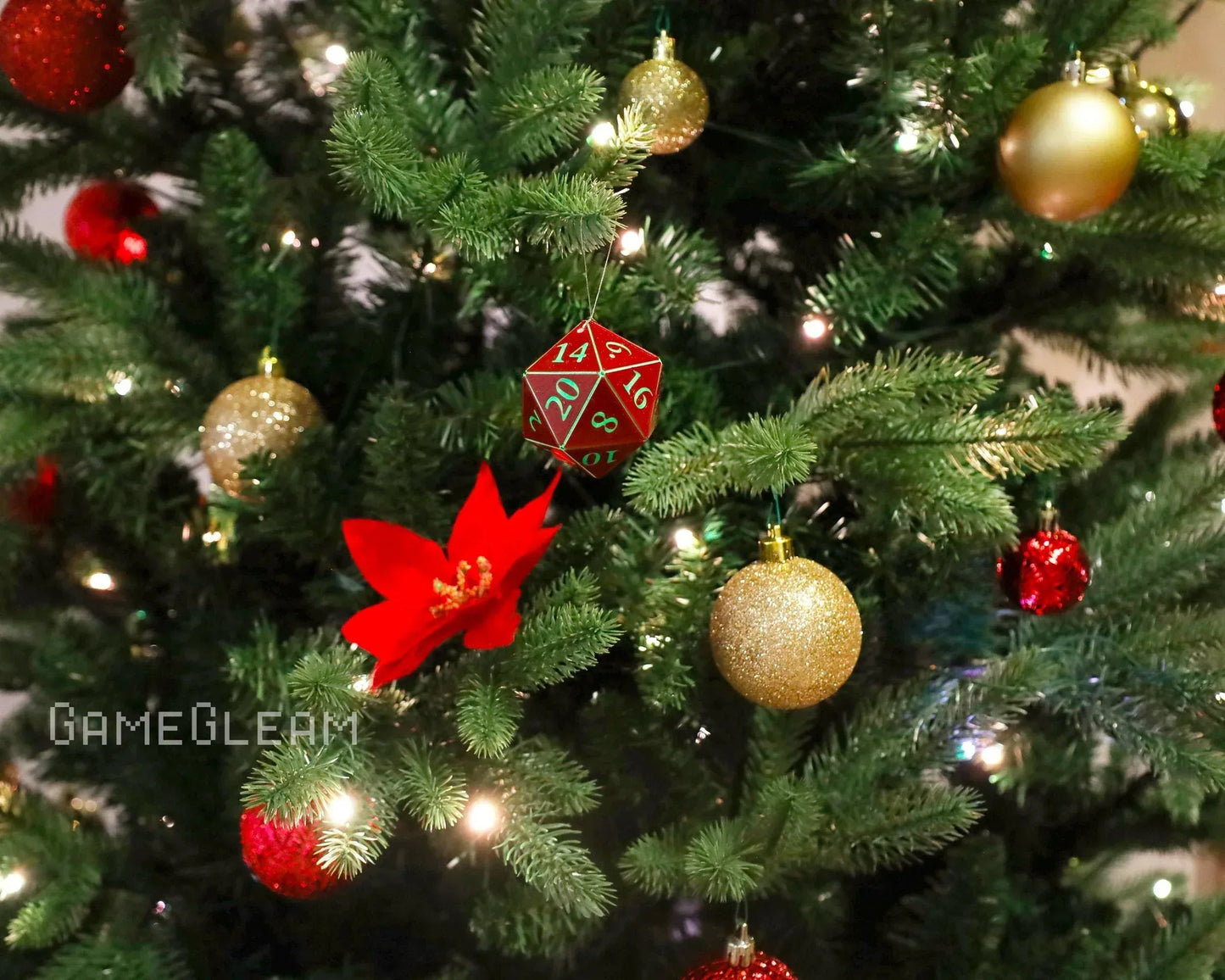 Red twenty-sided dice ornament hanging on a decorated Christmas tree with gold and red baubles.