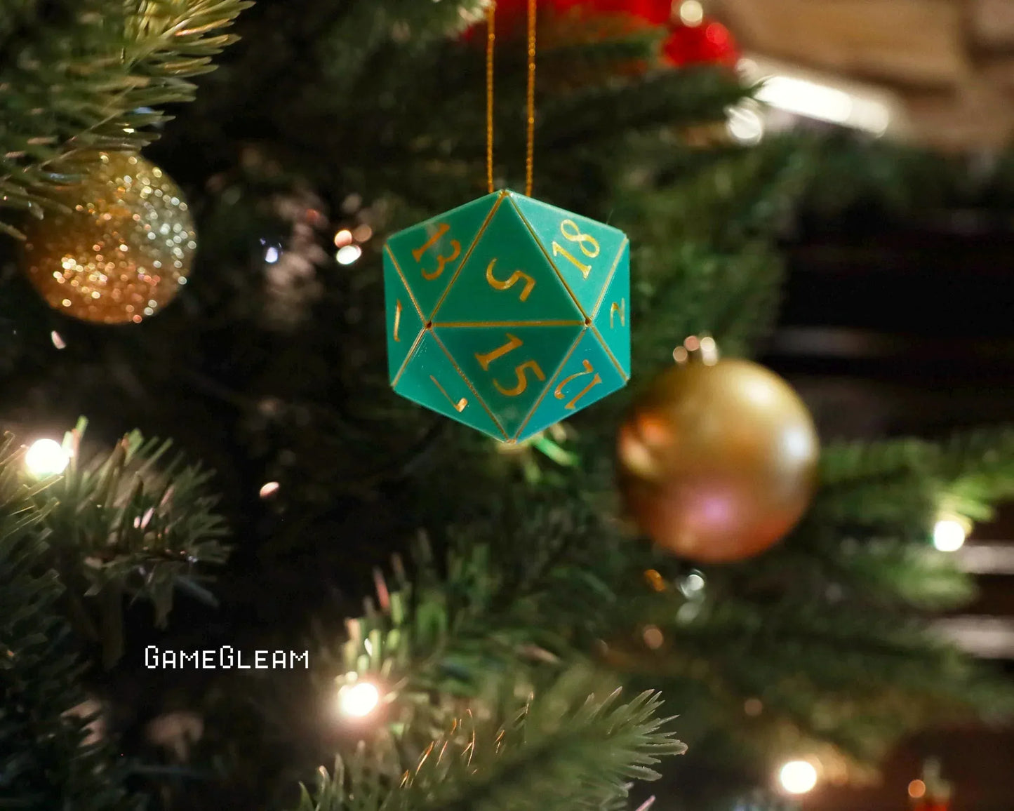 Green twenty-sided dice ornament with gold numbers hanging on a Christmas tree.