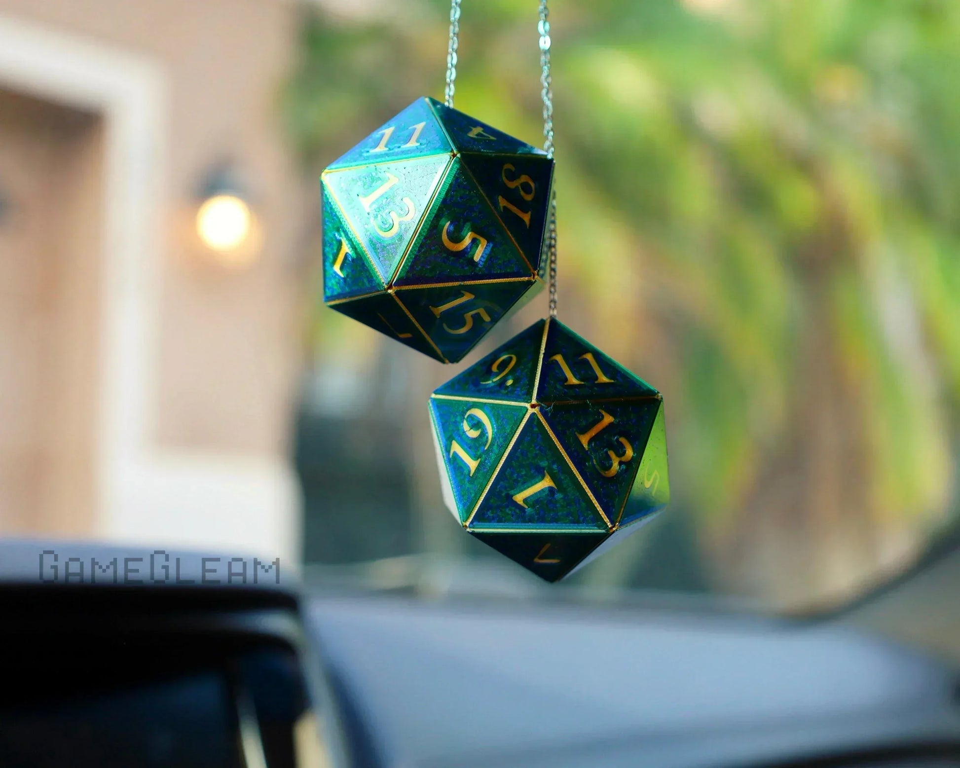 Holographic blue-green twenty-sided dice car charms hanging from a rearview mirror