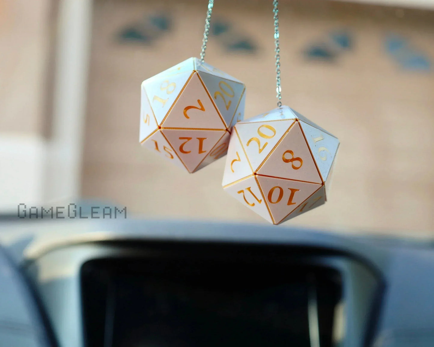 Pair of white and gold twenty-sided dice hanging as car mirror charms