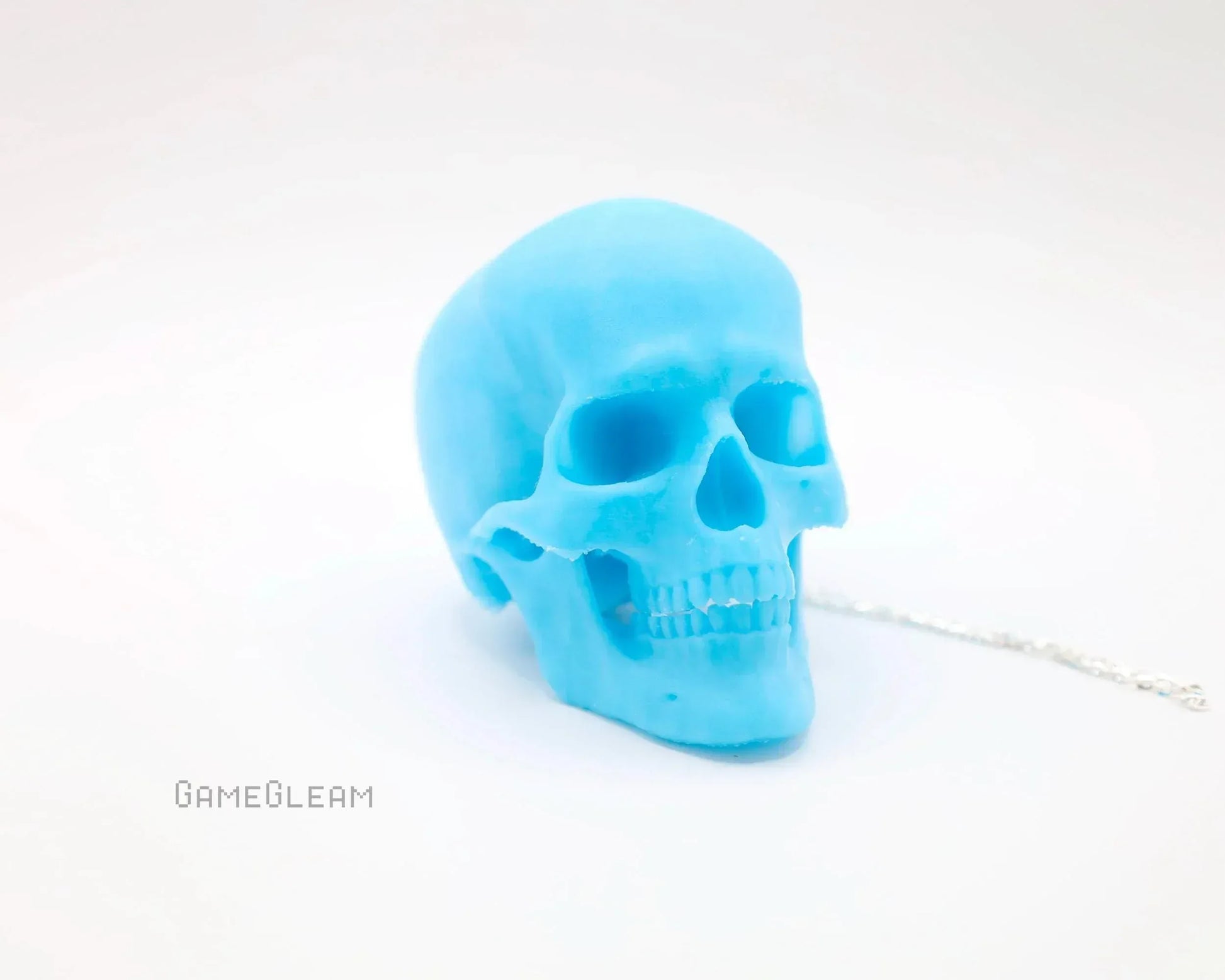 Bright blue resin skull charm with silver chain on white background, gamer accessory