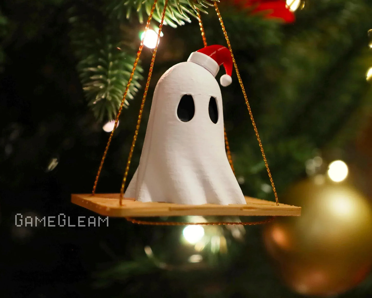 Handmade ghost ornament with Santa hat on swing, hanging on Christmas tree branch