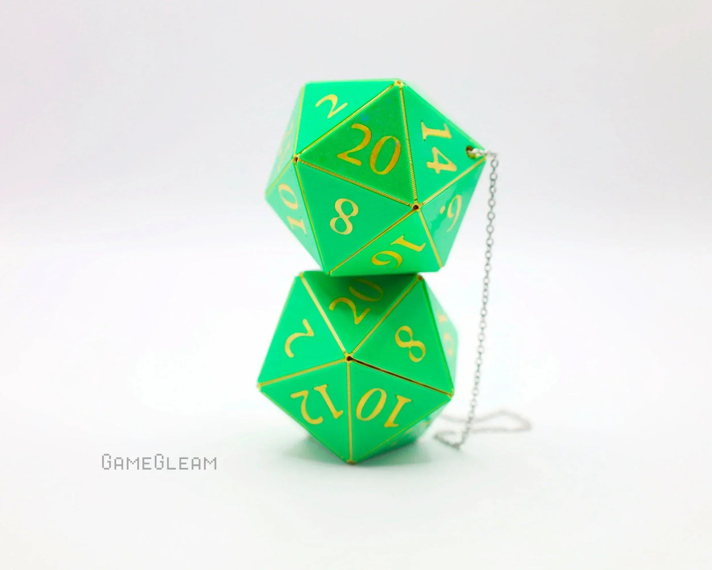 Two green 20-sided car dice charms with gold numbers and chain on white background