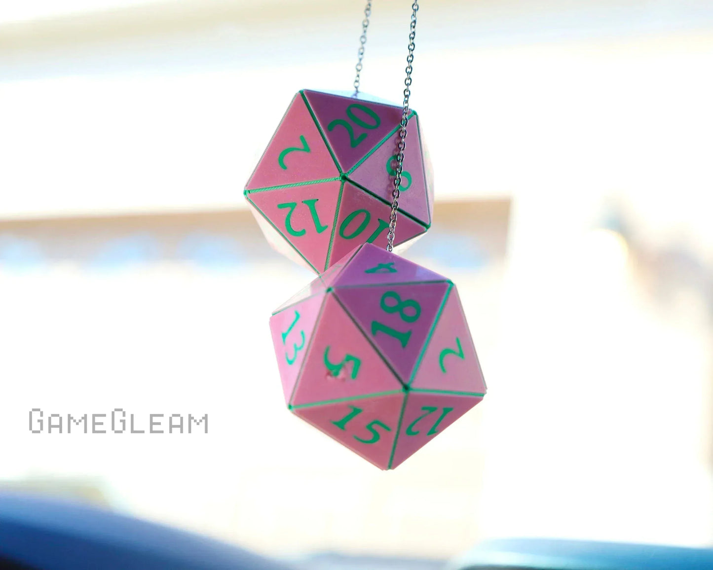 Pink holographic twenty-sided dice car charm with green numbers hanging from a chain