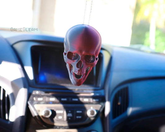 Red and black skull car charm hanging from rearview mirror in a modern vehicle interior.