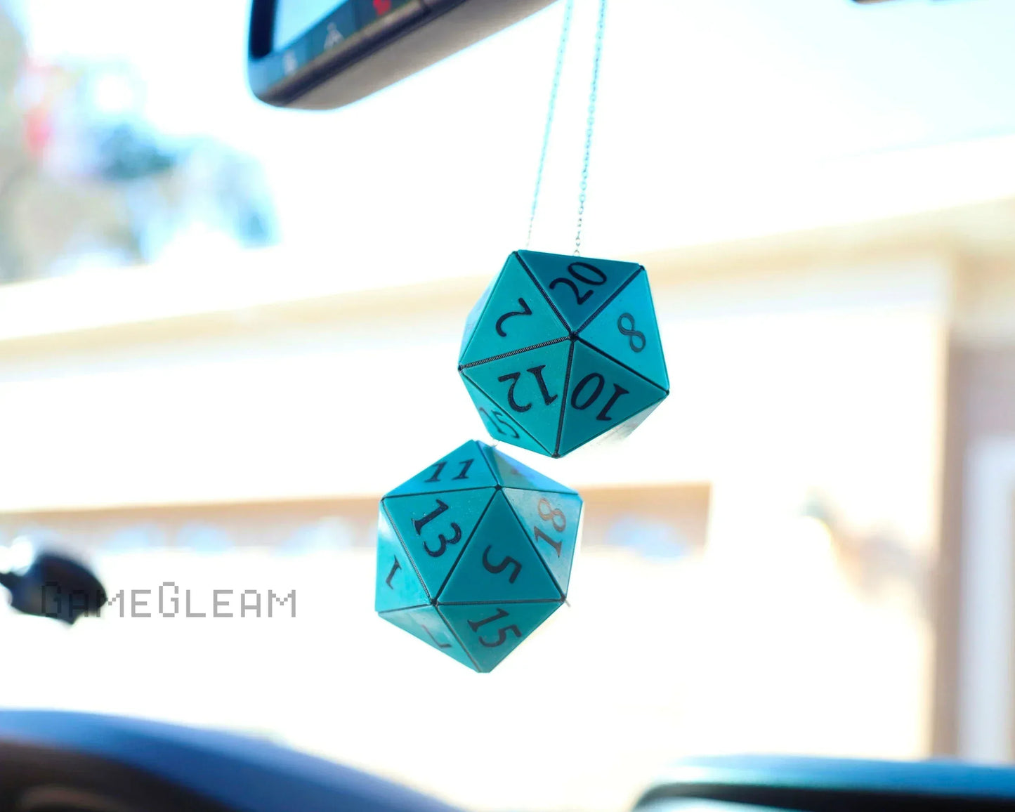 Turquoise twenty-sided dice hanging as car mirror charm with black numbers.