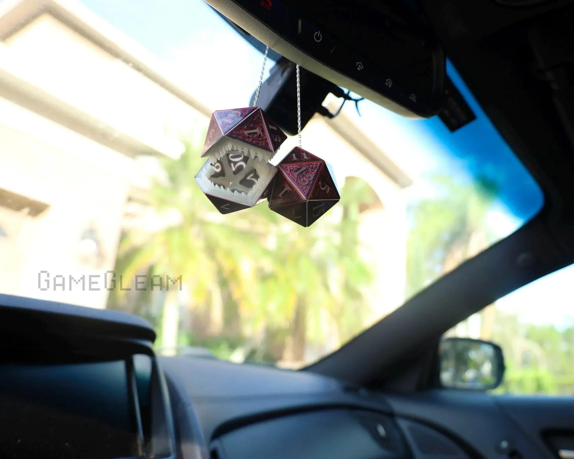 Hanging car dice charms shaped like red and silver polyhedral gaming dice in a car interior.
