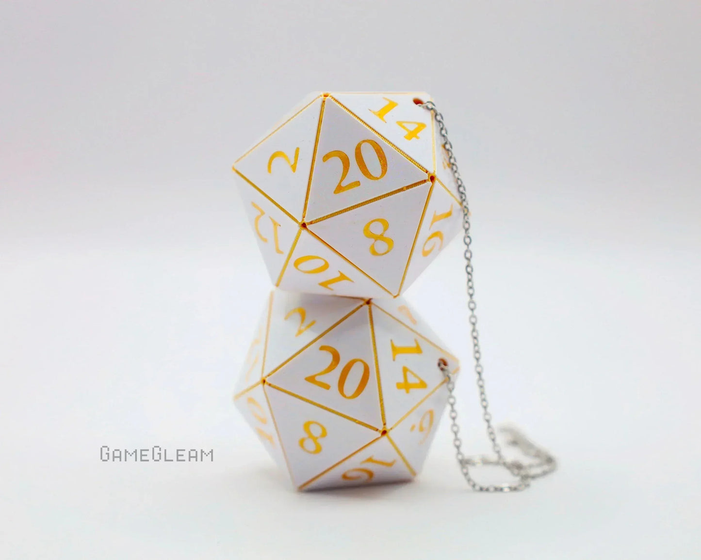 White twenty-sided dice car charms with gold numbers and a silver chain on a plain background.