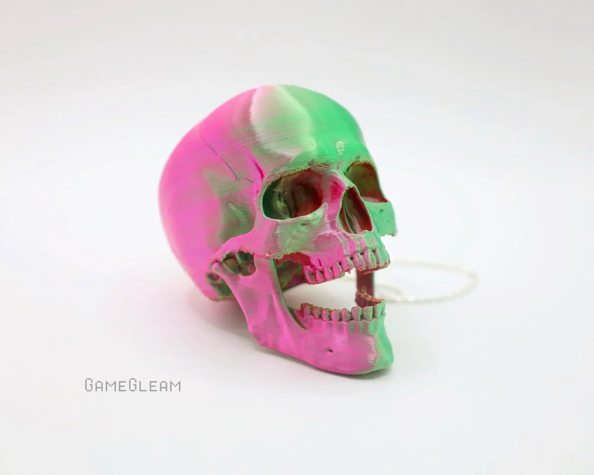 Handmade pink and green resin skull decor with chain on white background