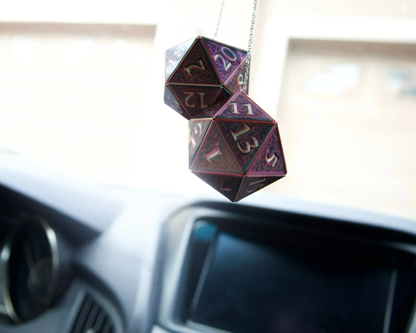 Holographic twenty-sided dice car charm hanging from rearview mirror in vehicle interior
