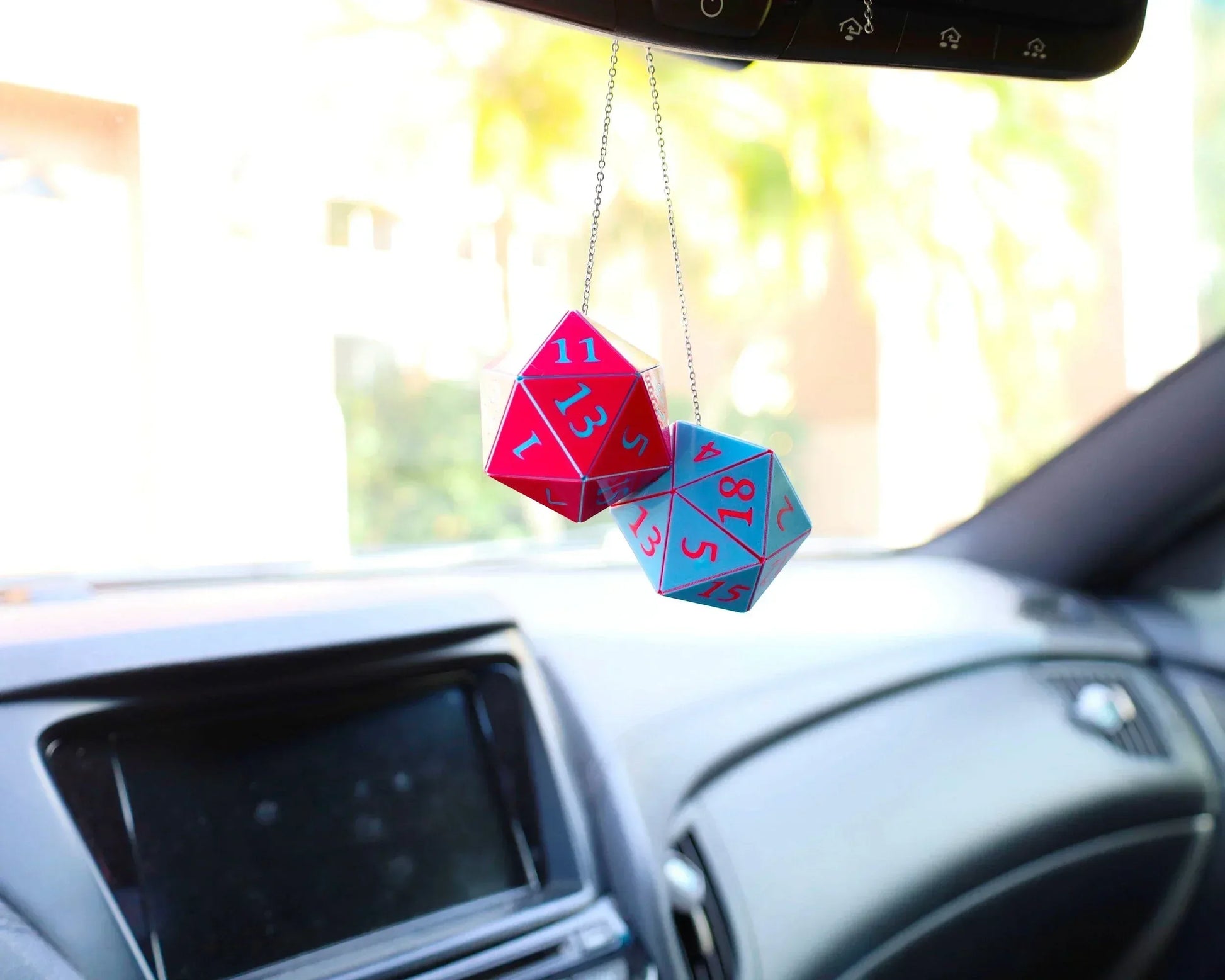 Holographic red and blue twenty-sided dice car mirror charm inside a vehicle