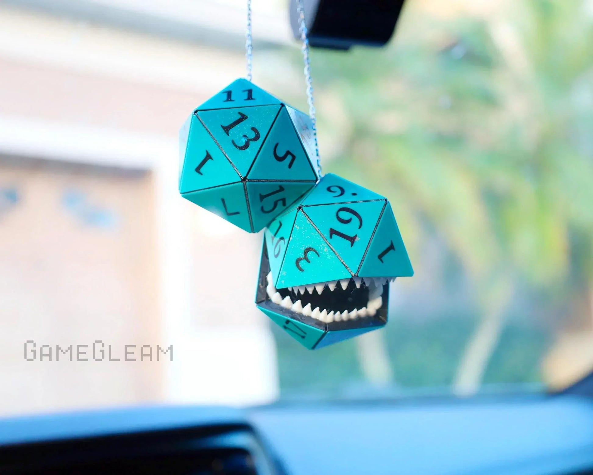 Turquoise twenty-sided dice car charm with one dice featuring teeth, hanging from rearview mirror