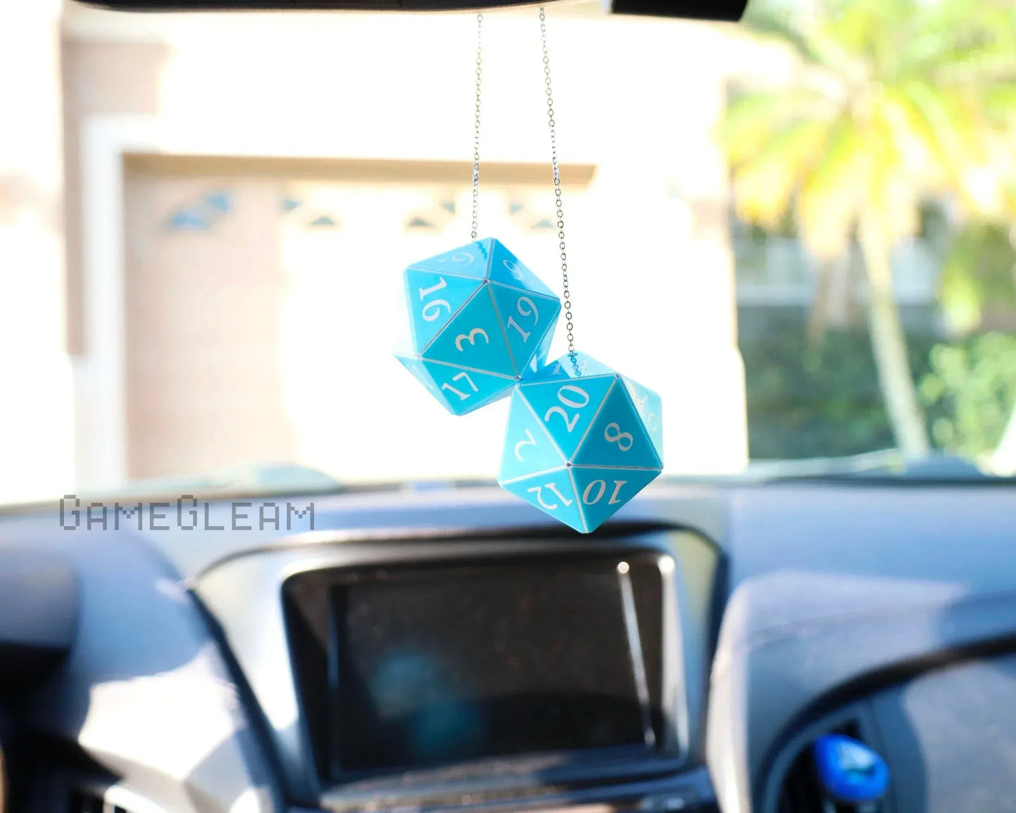 Blue twenty-sided dice car charm hanging from rearview mirror in a parked vehicle.