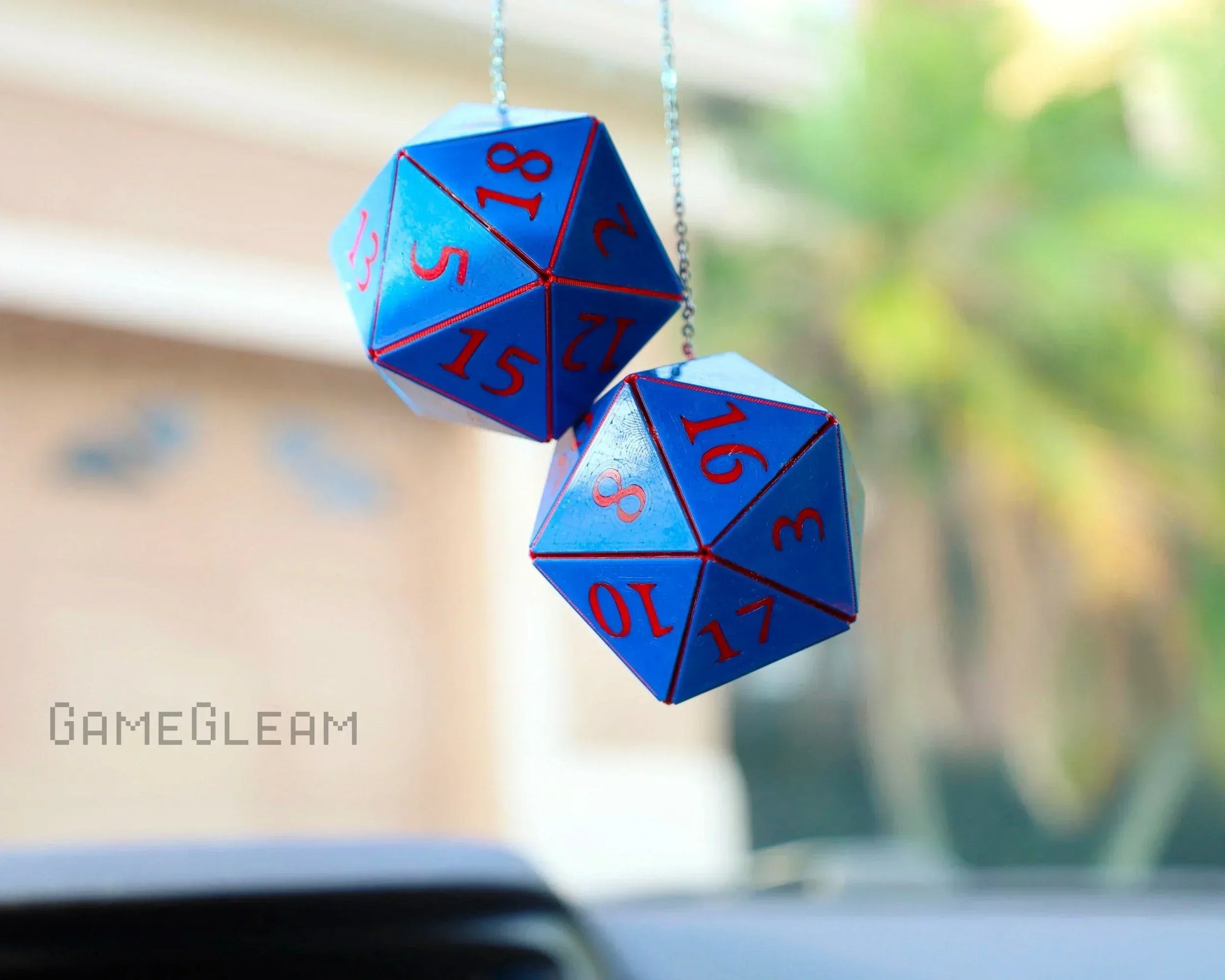 Blue twenty-sided dice car charm with red numbers hanging from rearview mirror