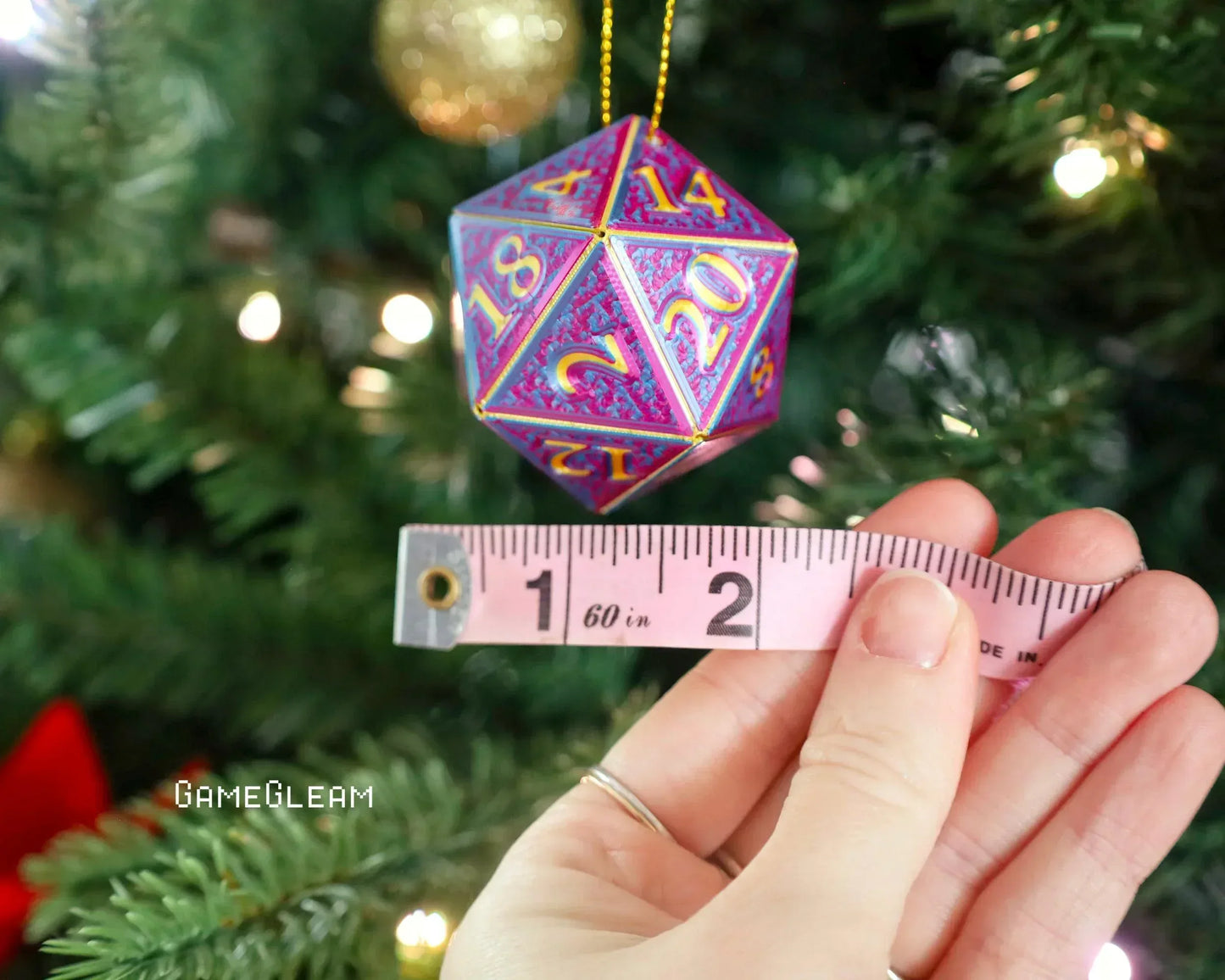 Holographic twenty-sided dice ornament measured with a tape, hanging on a Christmas tree