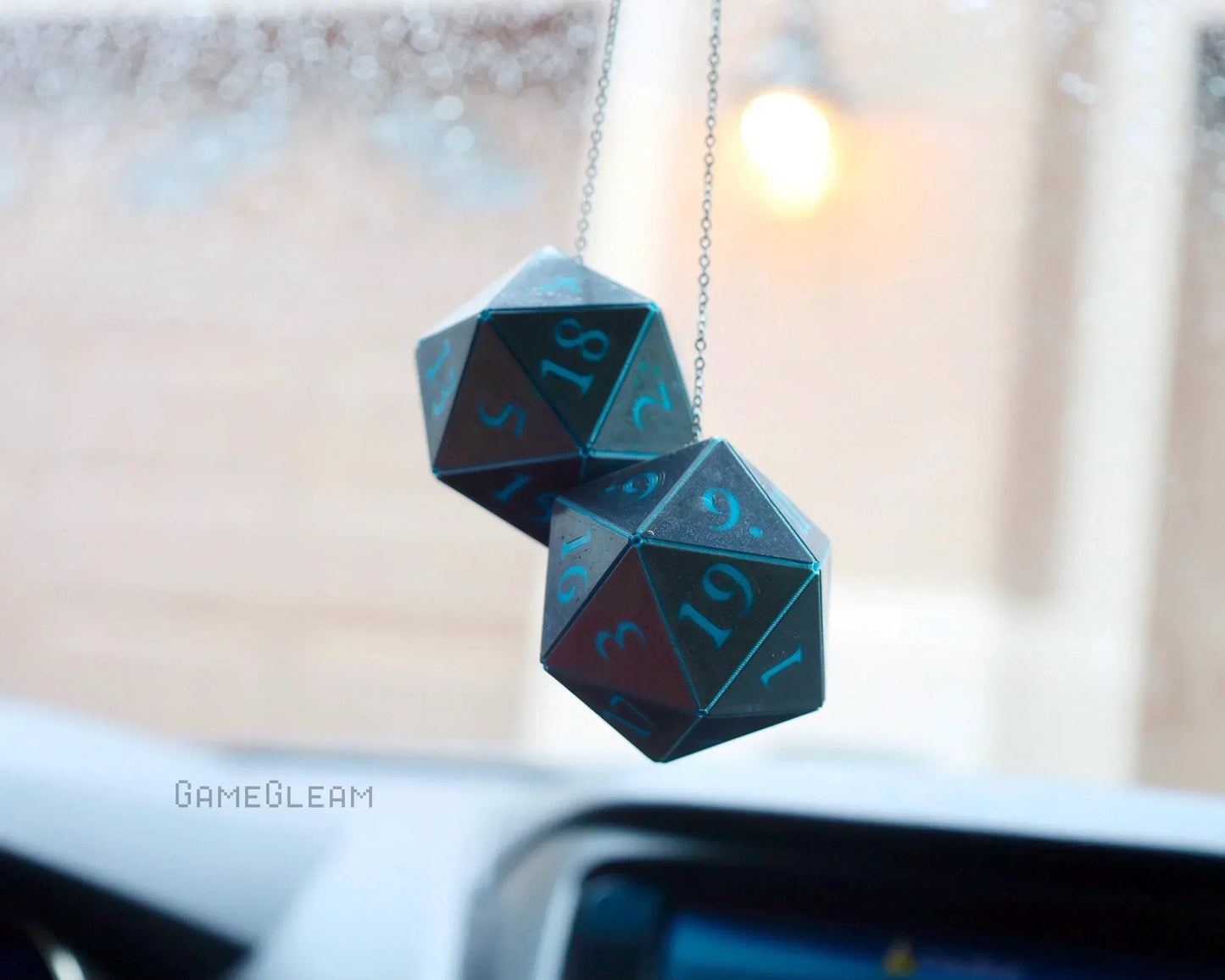Holographic teal twenty-sided dice car charm hanging from a rearview mirror