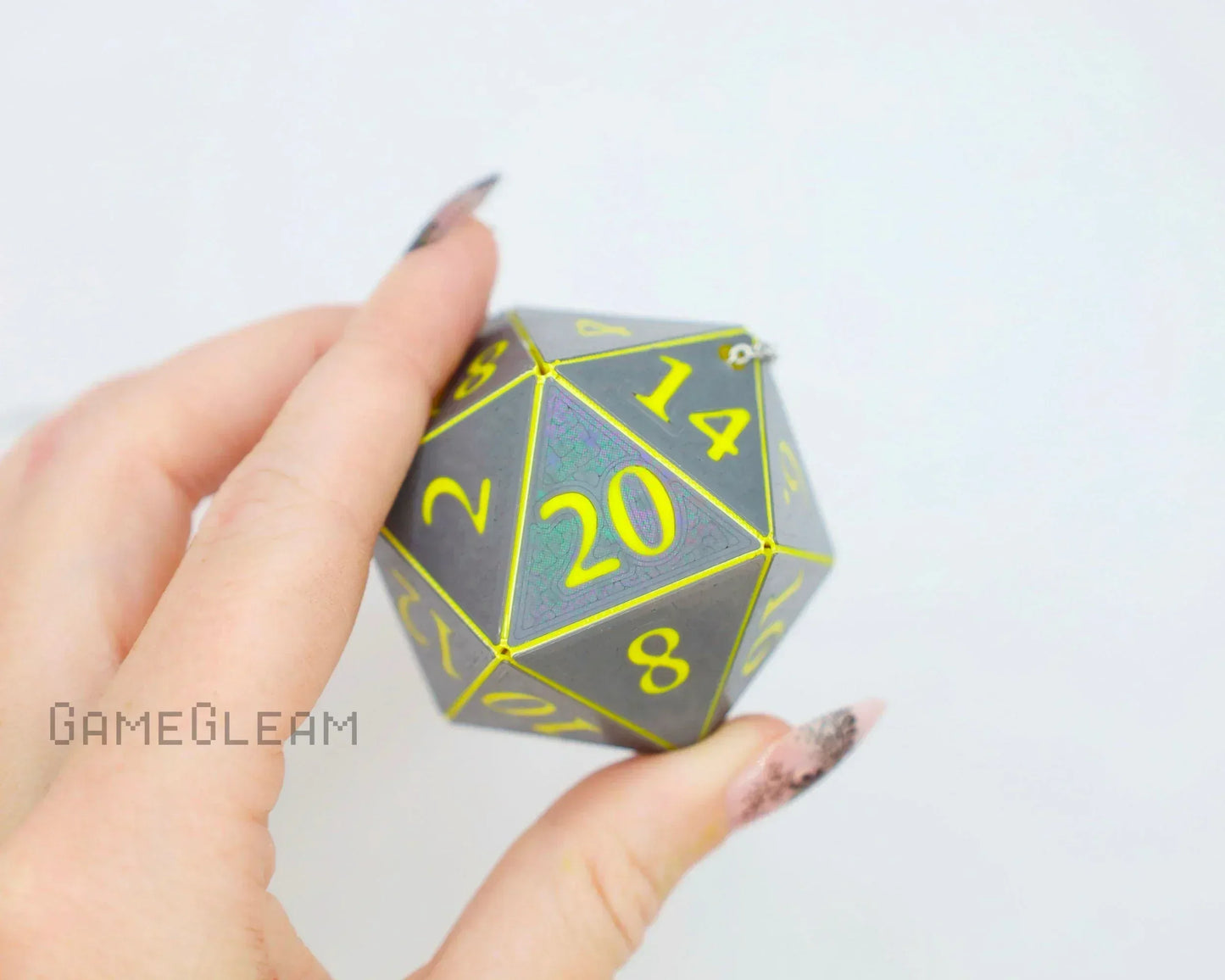 Hand holding a large holographic twenty-sided dice charm with yellow numbers