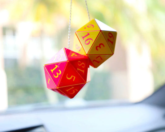 Hanging red and yellow twenty-sided dice car charm in bright sunlight, gamer car accessory