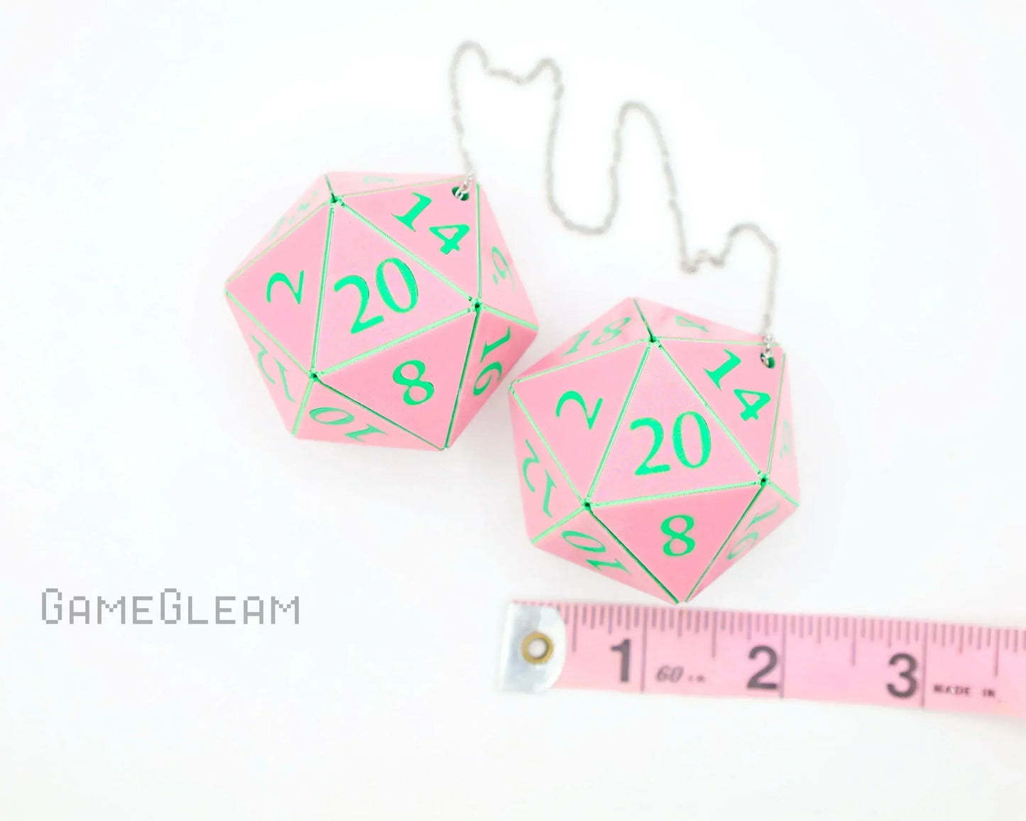 Pink 20-sided dice car accessories with green numbers and a measuring tape