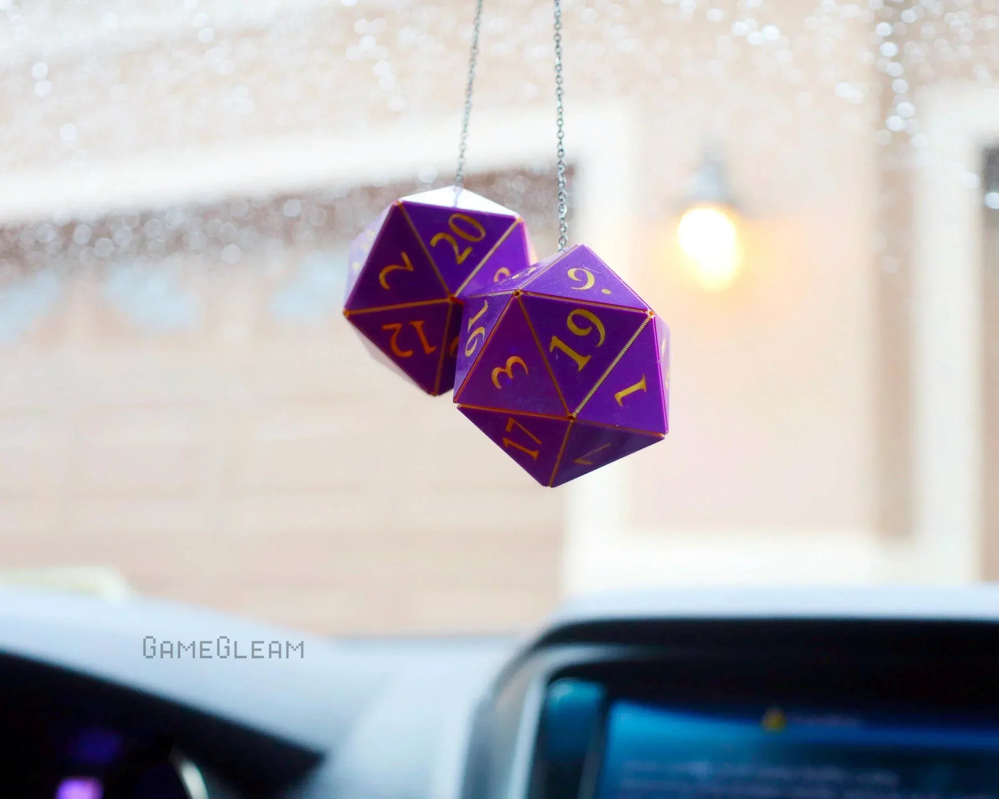Purple twenty-sided dice car charm with gold numbers hanging from rearview mirror