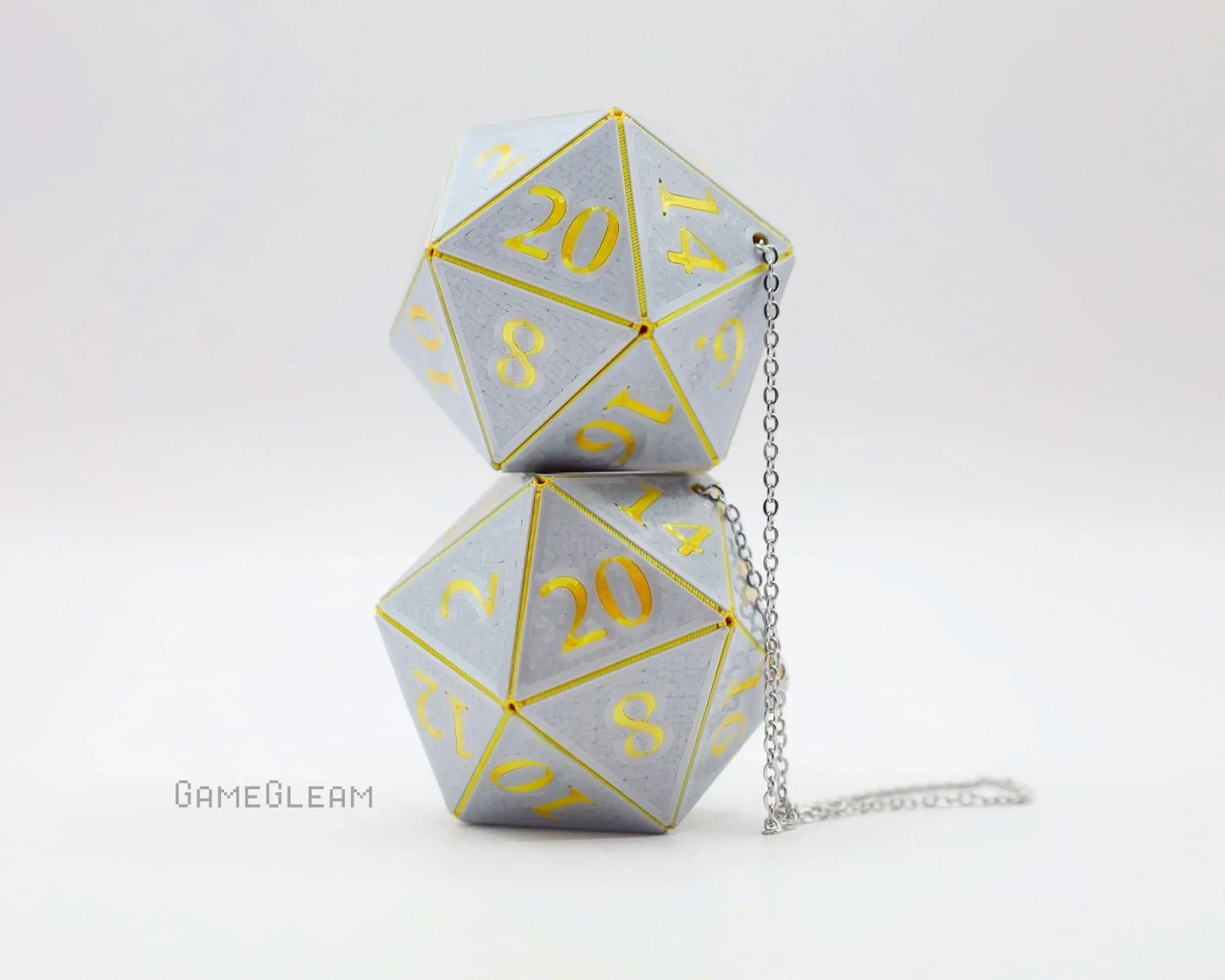 Pair of silver 20-sided dice with gold numbers and a silver chain, tabletop gaming decor.