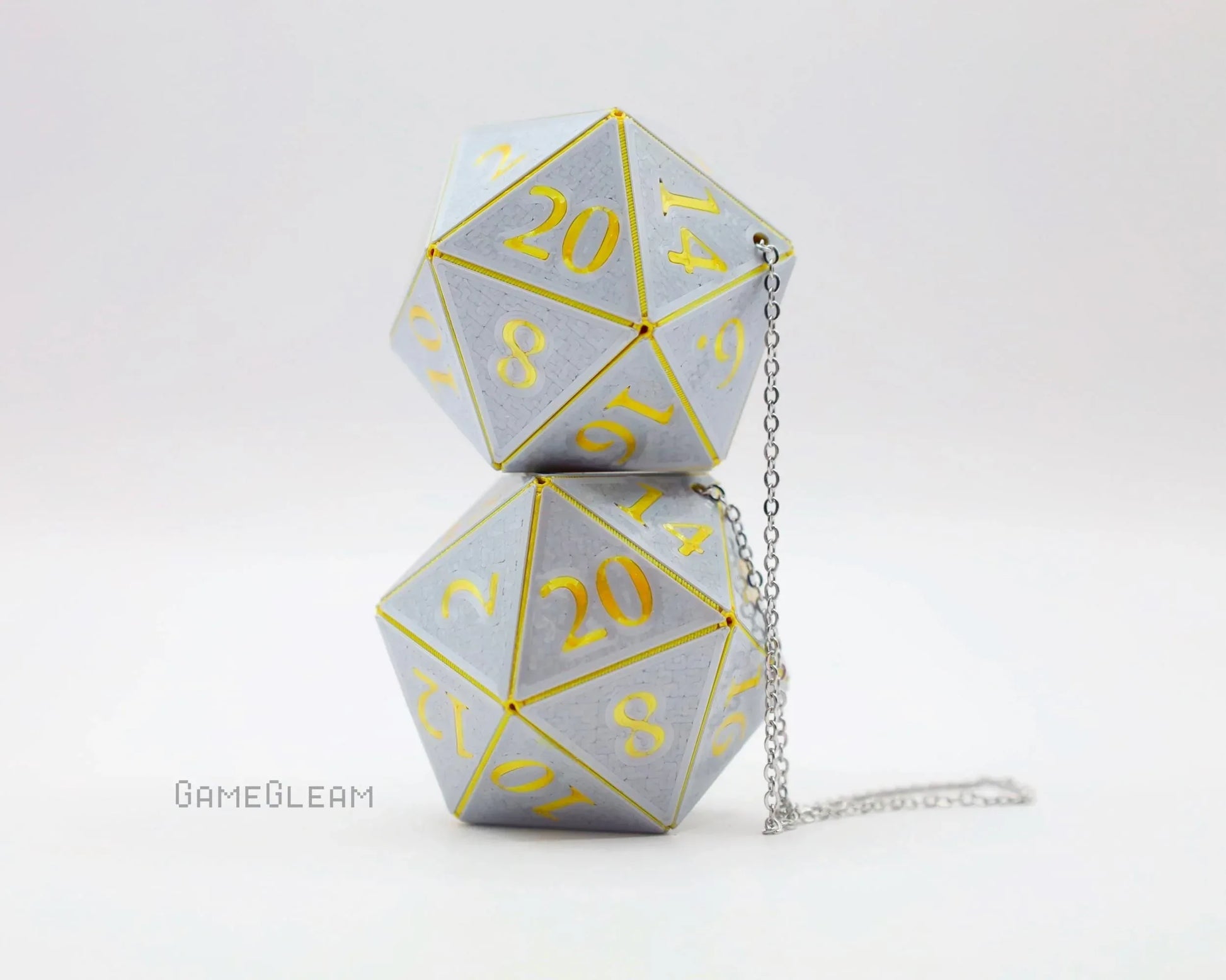 Pair of silver 20-sided dice with gold numbers and a silver chain, tabletop gaming decor.