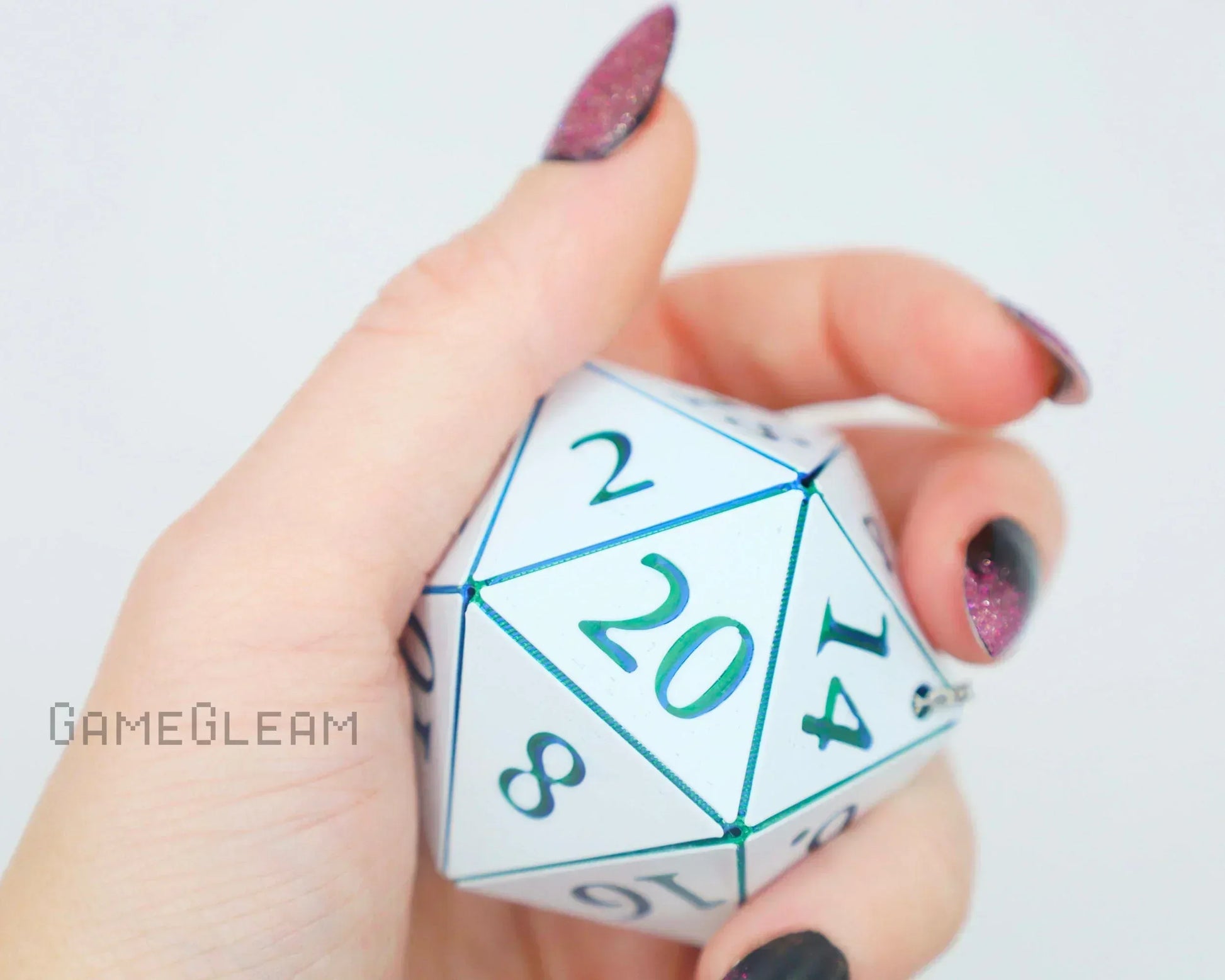 Hand holding large white 20-sided dice with green numbers, close-up, gamer accessory