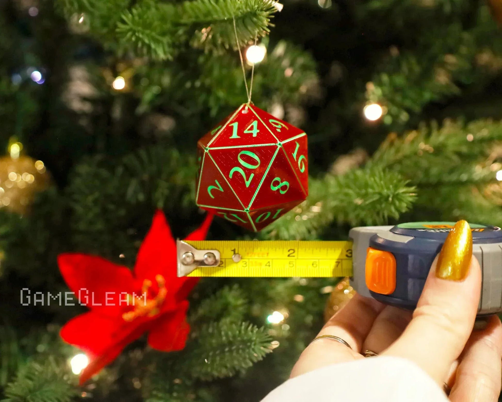 Red twenty-sided dice ornament hanging on a Christmas tree, measured with tape measure.