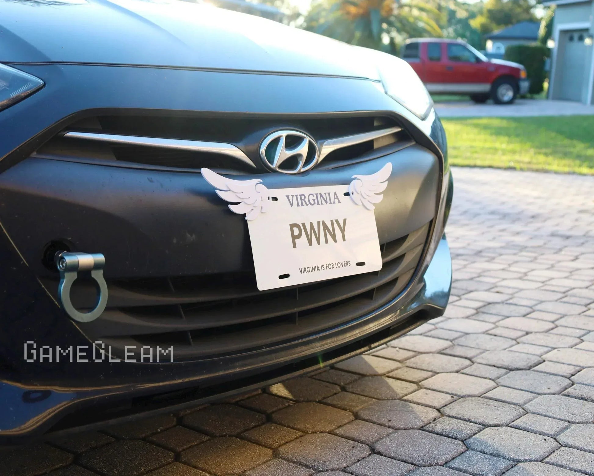 Close-up of a Hyundai car front with a novelty license plate displaying winged accents and the word PWNY.