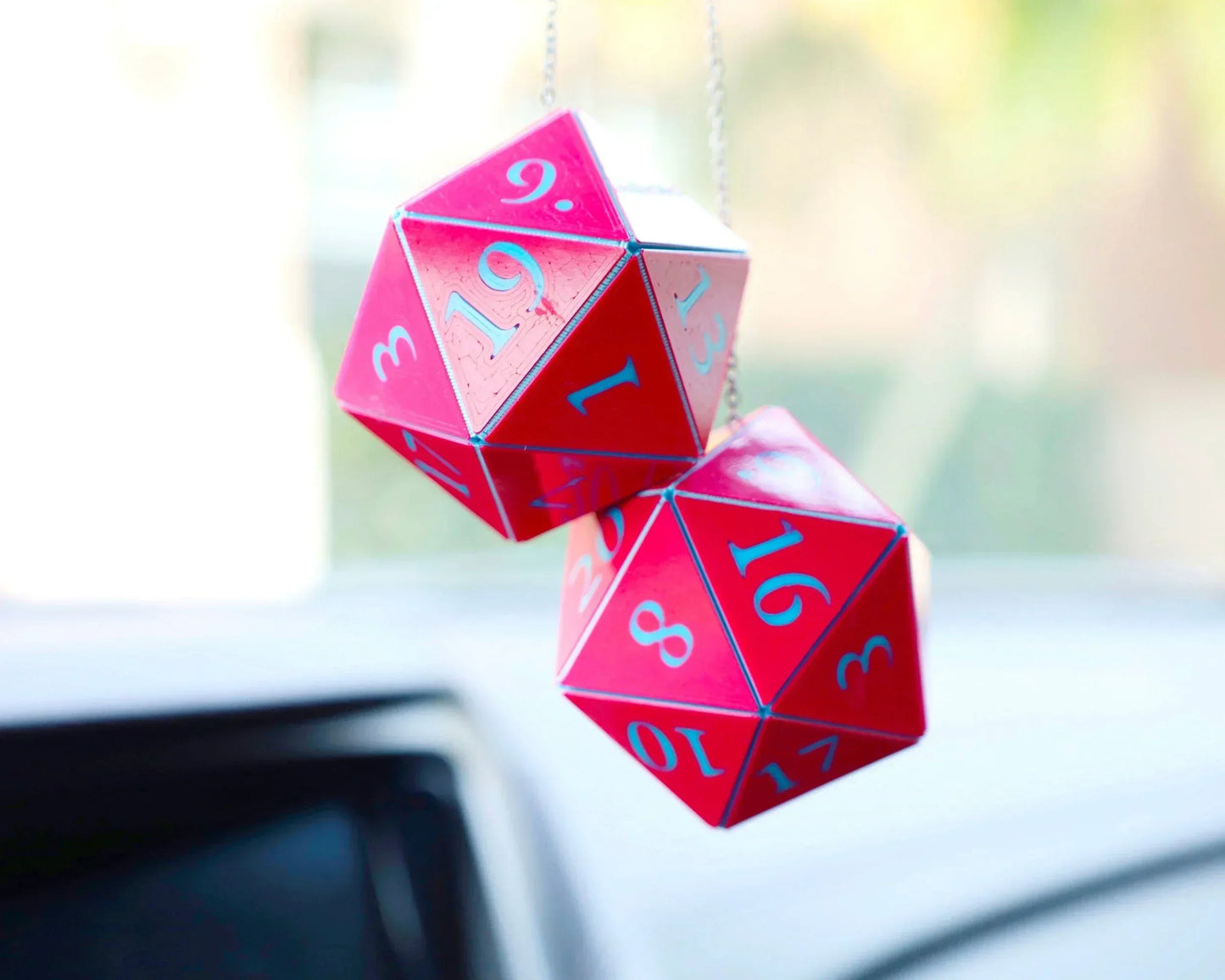 Red twenty-sided dice car hanging charm with blue numbers, close-up in vehicle