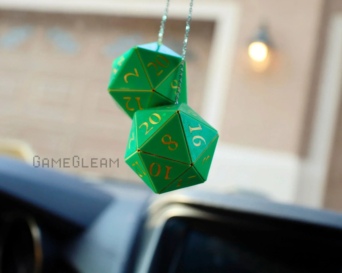 Green twenty-sided dice car mirror charm with yellow numbers, hanging in a vehicle
