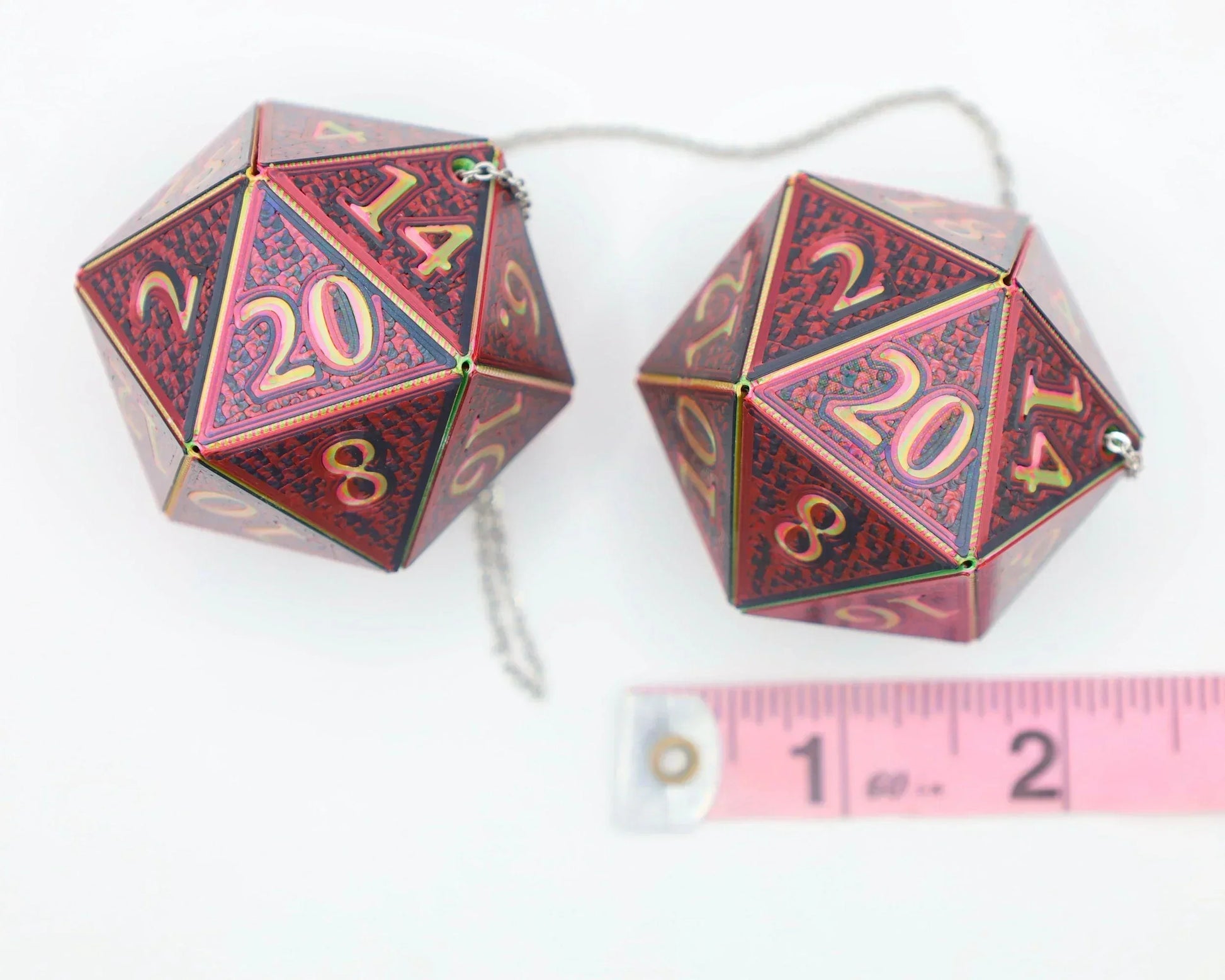 Pair of large red holographic 20-sided dice car charms with chain, shown next to ruler