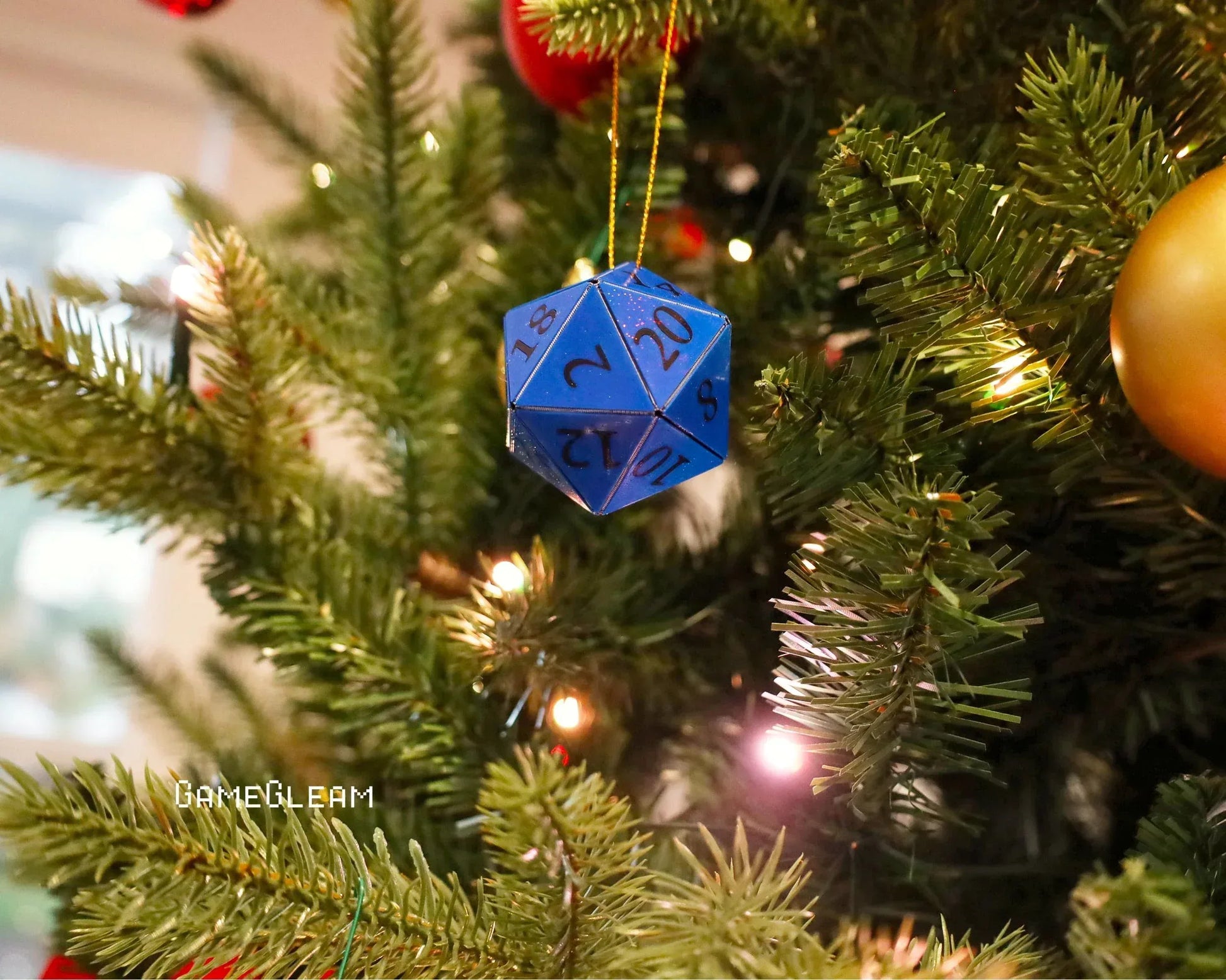 Blue twenty-sided dice ornament hanging on a decorated Christmas tree