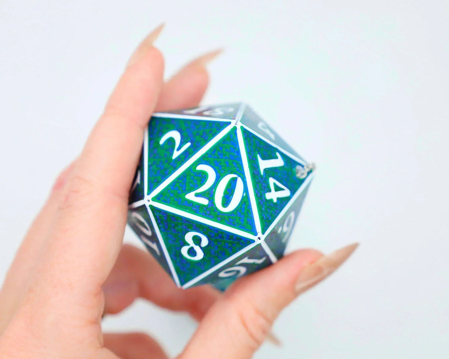 Hand holding a holographic green and blue 20-sided dice with white numbers