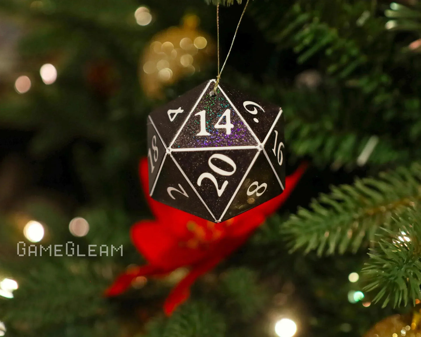 Black glittery polyhedral twenty-sided dice ornament hanging on a Christmas tree branch
