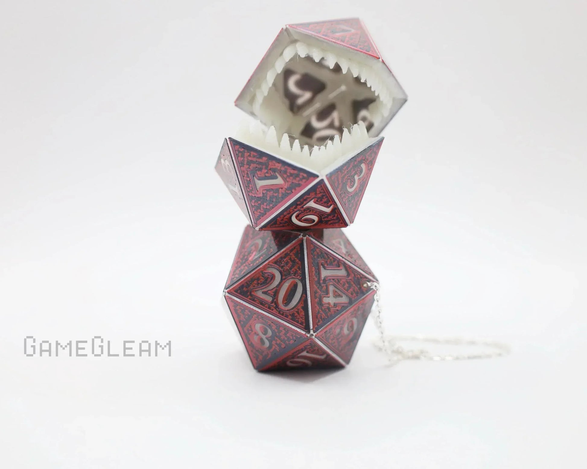 Handmade red polyhedral dice monster charm with open mouth and sharp teeth, chain attached.