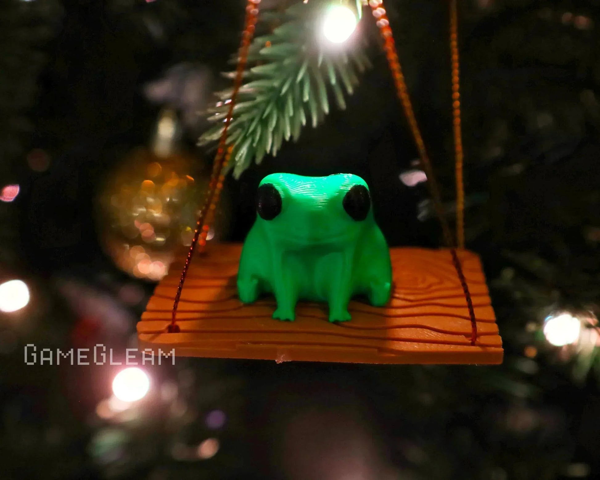 Green frog figurine on a wooden swing ornament hanging on a Christmas tree branch