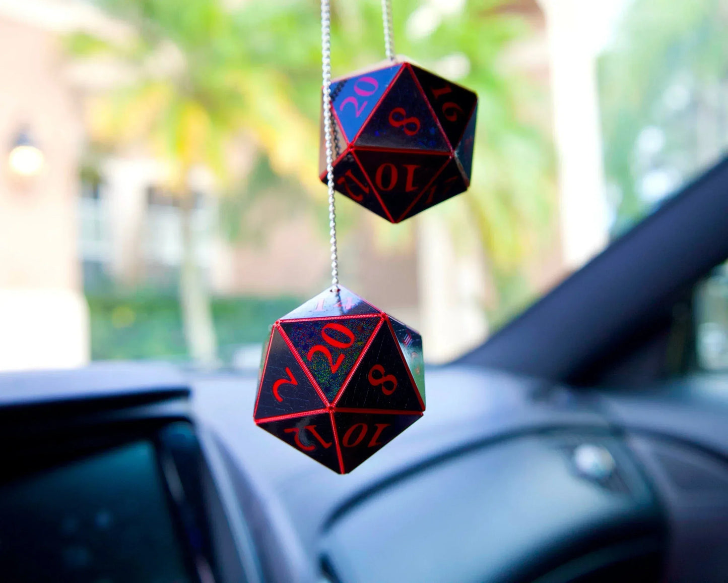 Holographic red and black 20-sided dice car charm hanging in vehicle interior