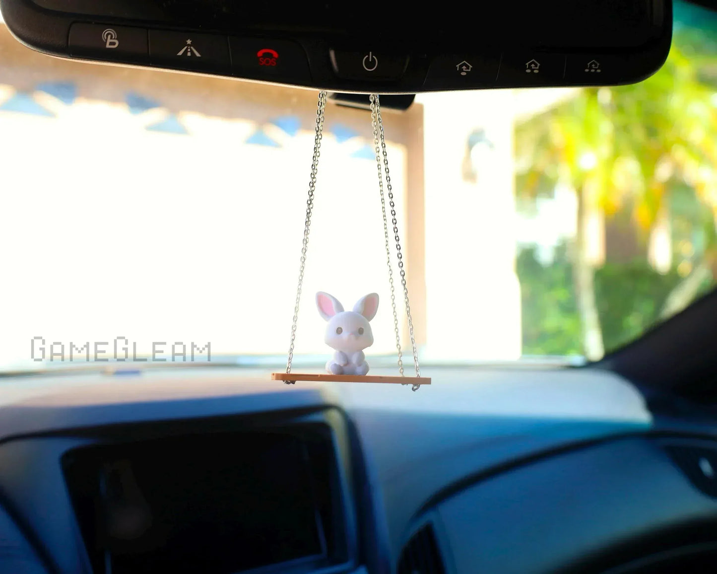 Cute bunny car charm on a swing hanging from rearview mirror, playful dashboard accessory