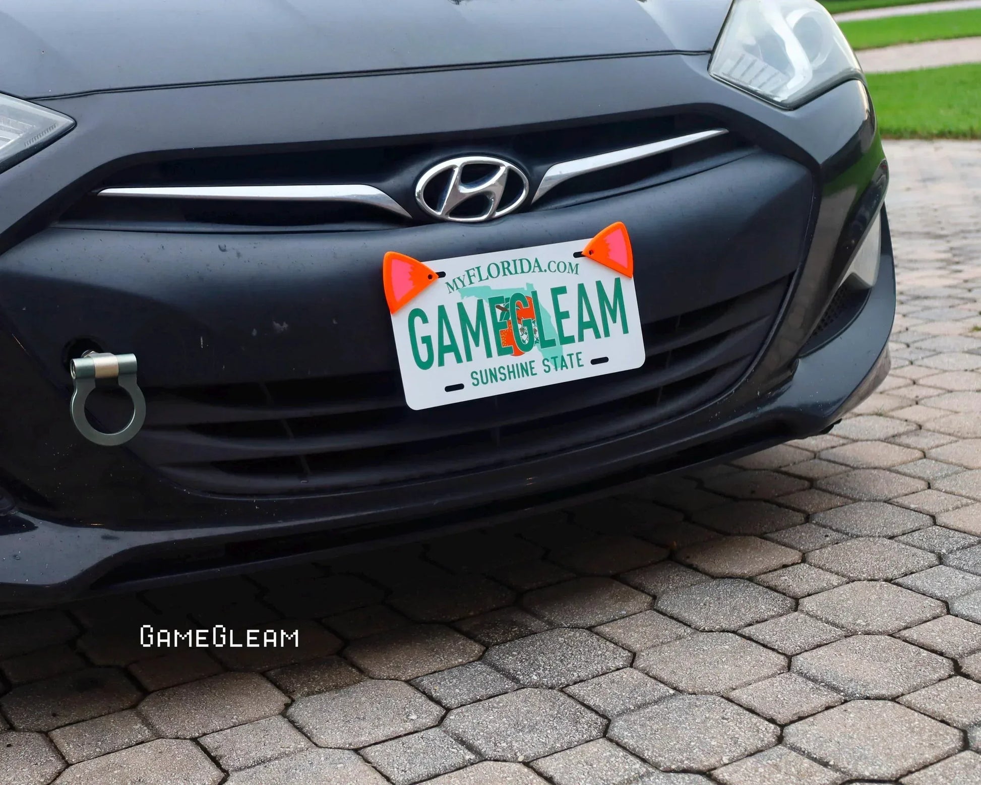 Black Hyundai car with custom Florida gamer-themed license plate and orange cat ear accessories.