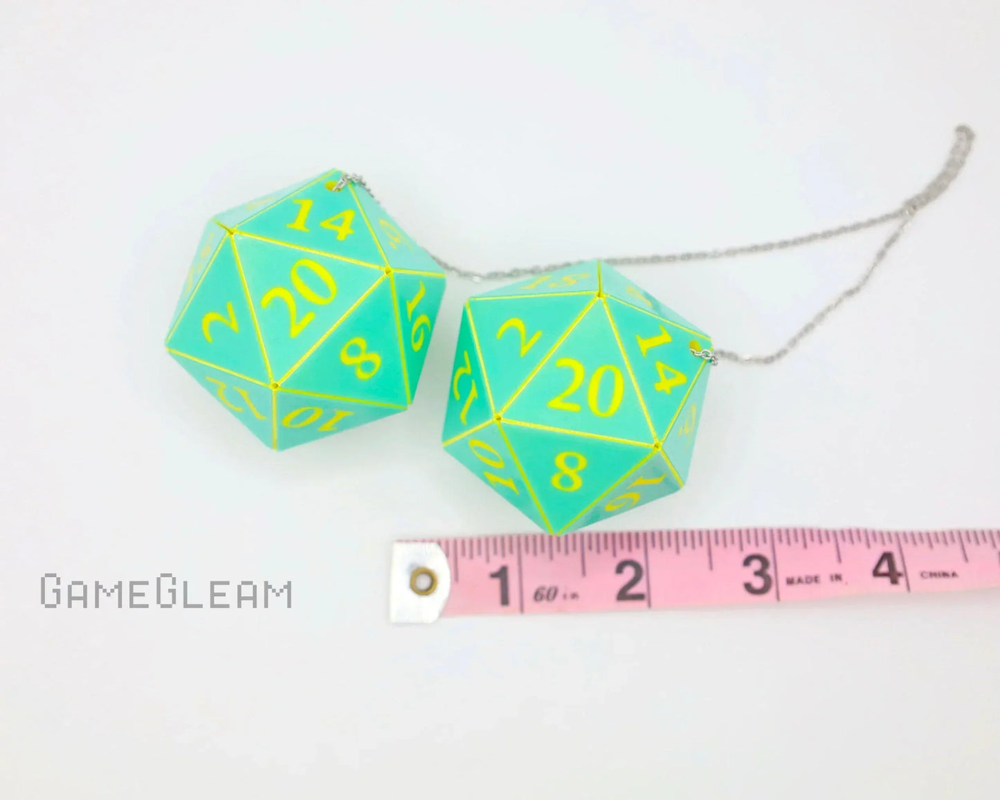 Aqua and yellow twenty-sided dice car charm on chain, shown next to a pink ruler for scale.