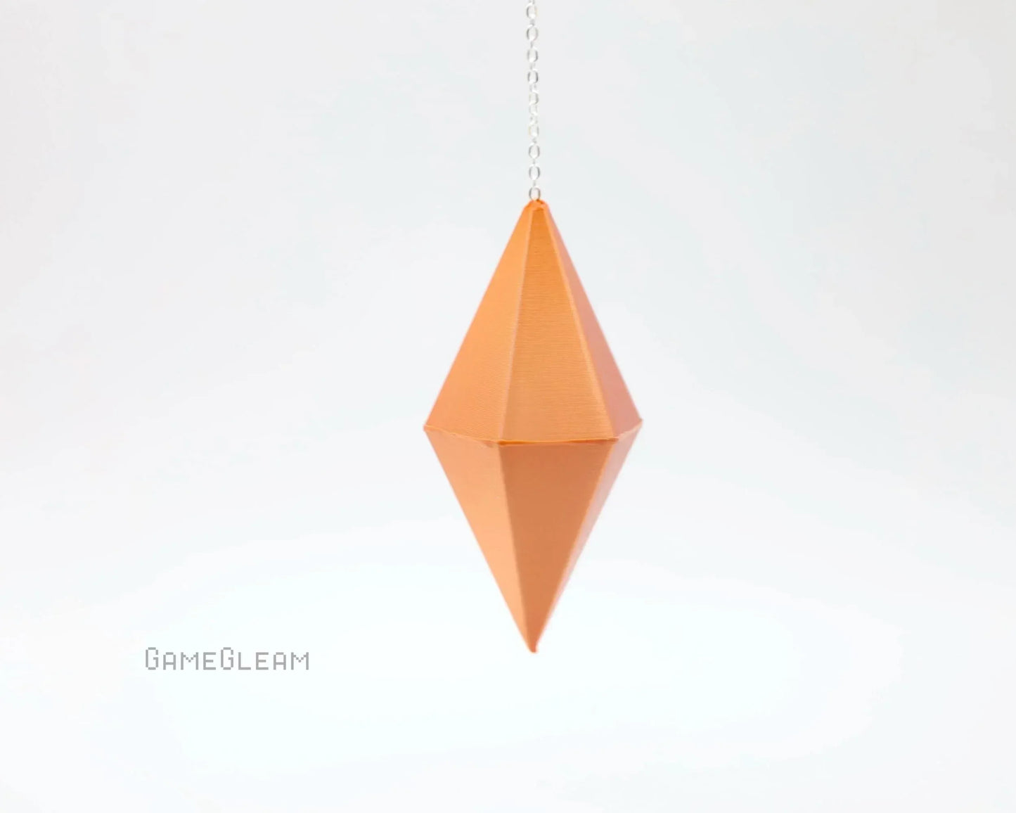 Geometric orange hanging dice charm with chain on white background, handmade gamer accessory