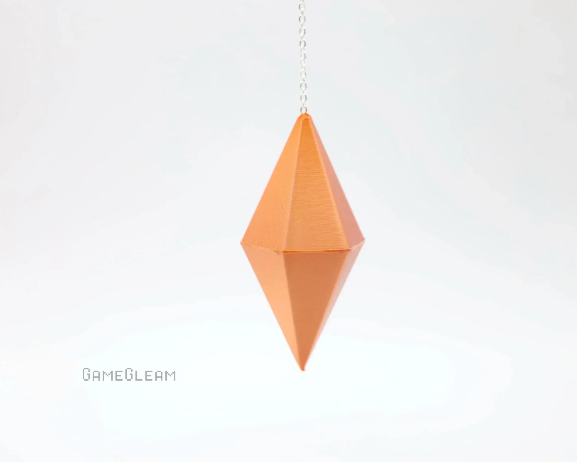 Geometric orange hanging dice charm with chain on white background, handmade gamer accessory