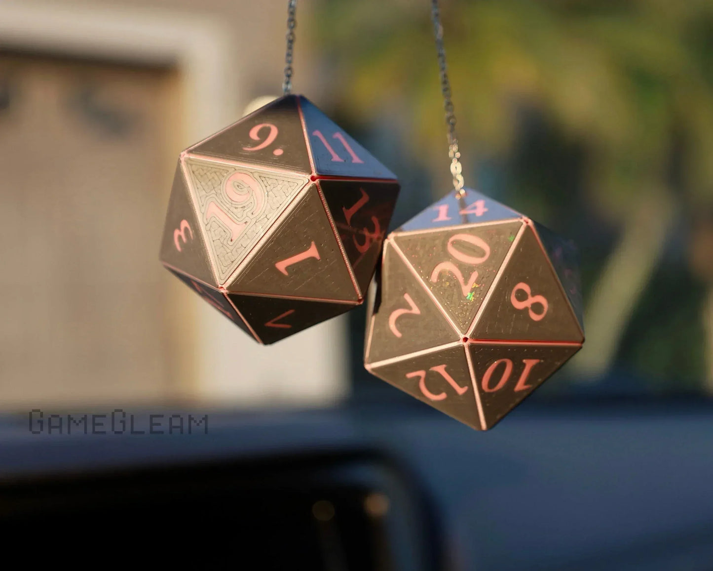 Pair of black and pink twenty-sided dice car charms hanging from rearview mirror