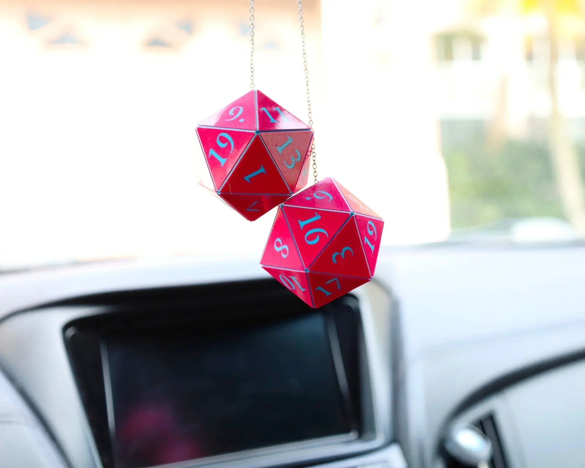 Red twenty-sided dice hanging from a car rearview mirror as a unique gamer accessory