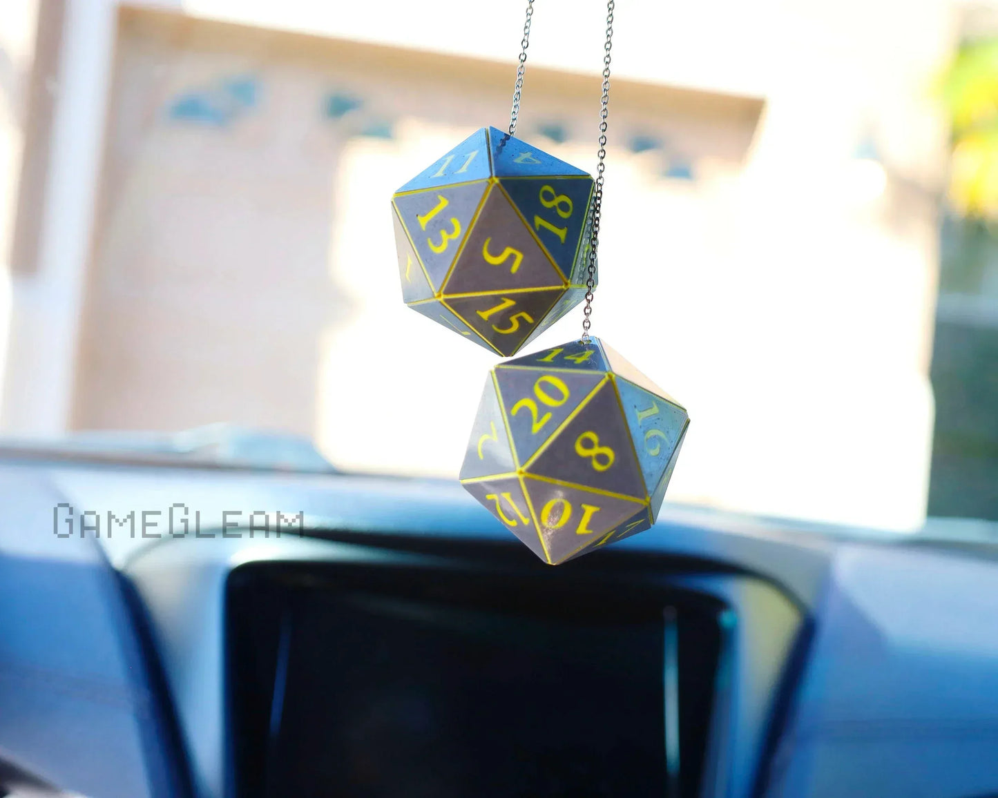 Holographic twenty-sided dice car charm with yellow numbers hanging from rearview mirror