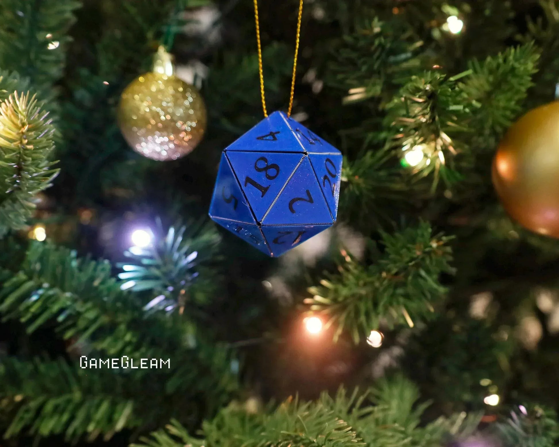 Blue twenty-sided dice ornament hanging on a Christmas tree with festive lights and baubles